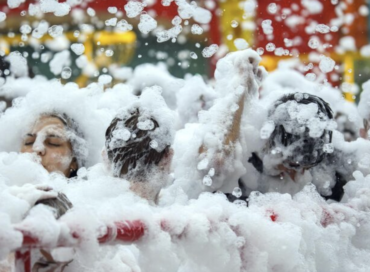 Commercial foam party cannon rental burying a pool deck in shoulder-deep foam at a Dallas Fort Worth HOA summer kickoff