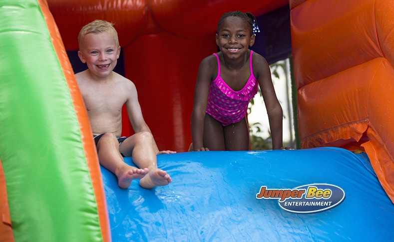 Two children playing on an inflatable water slide from Jumper Bee in Texas.